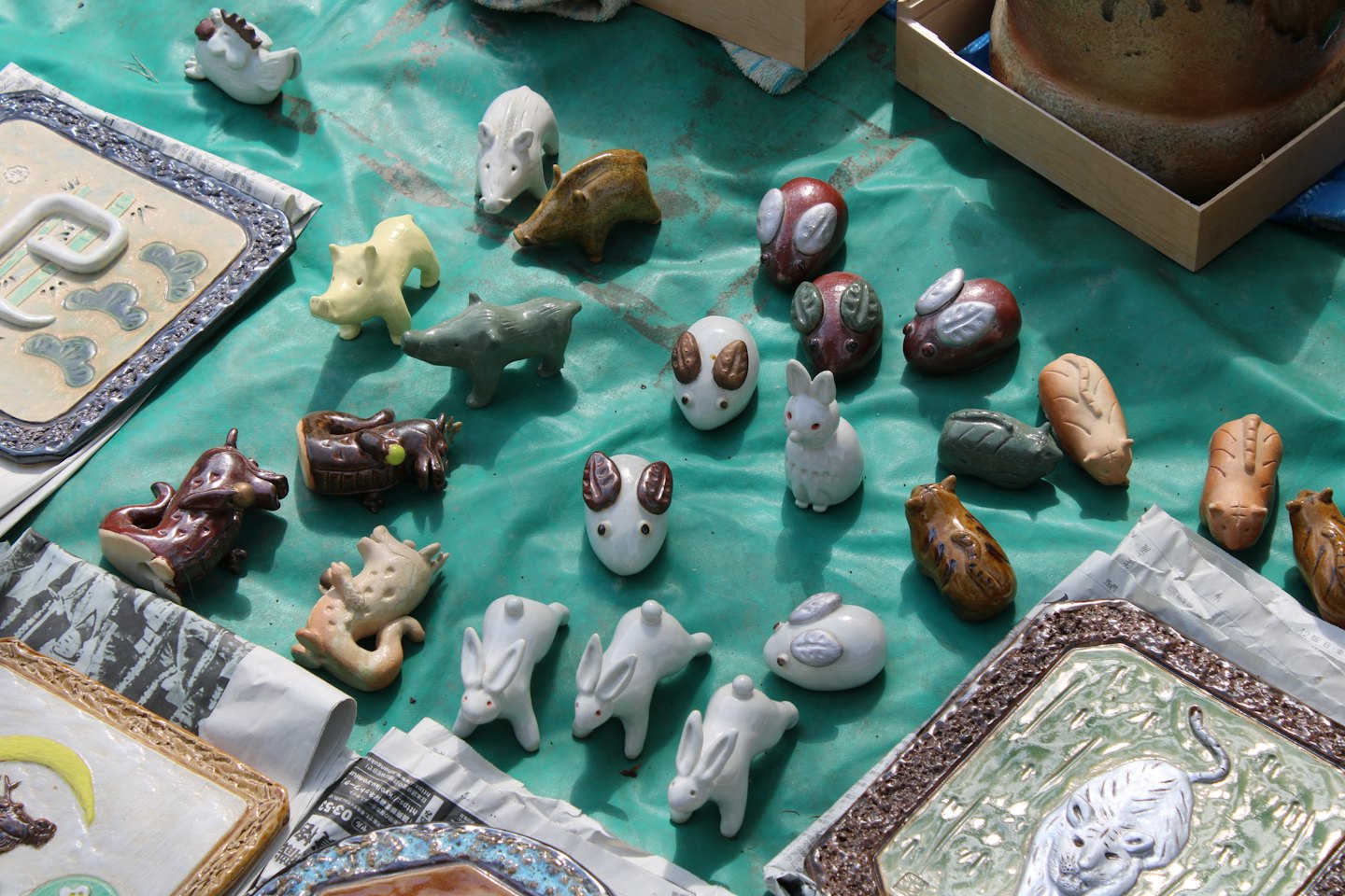 Handmade ceramic animal figurines displayed on a market tarp.