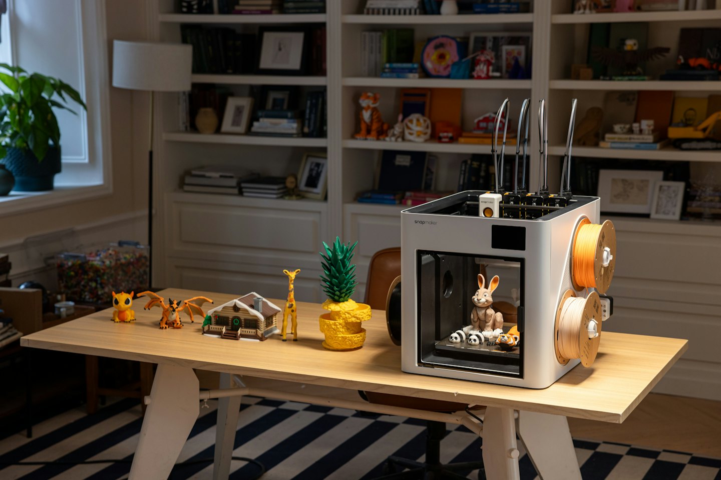 A 3D printer on a desk with colorful printed objects.